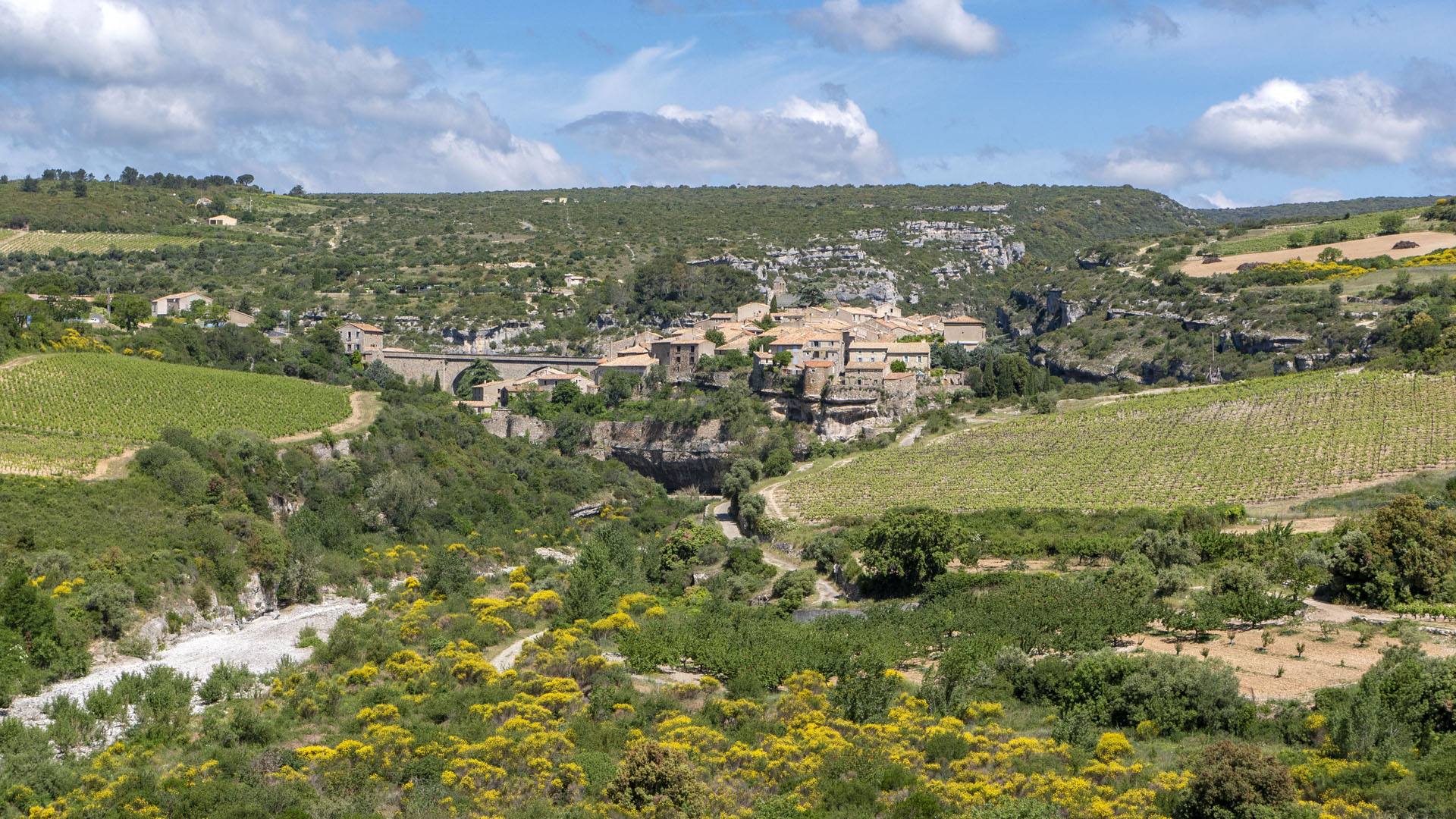 Visiting Minerve France: The town of Minerve from a distance, surrounded by hills.